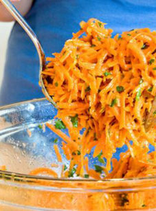 Person tossing a French grated carrot salad with lemon dijon vinaigrette.