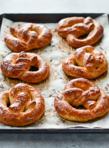 Soft pretzels on a lined baking sheet.