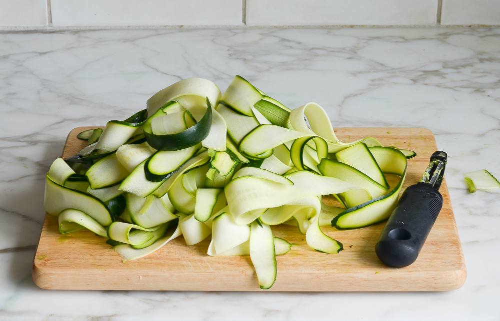 peeling the zucchini into wide ribbons