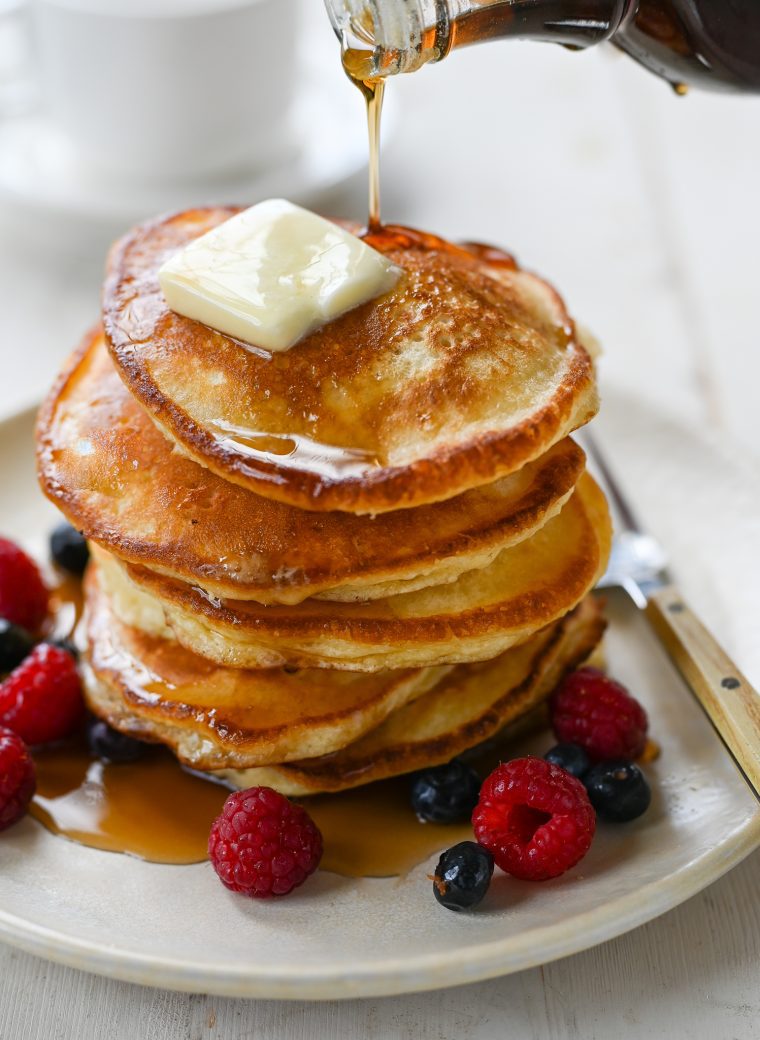 Syrup drizzling onto a stack of pancakes.