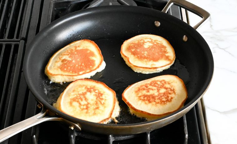 golden pancakes cooking on second side