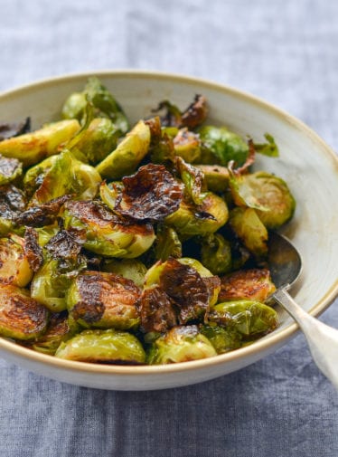 Spoon in a bowl of roasted brussels sprouts with balsamic vinegar and honey.