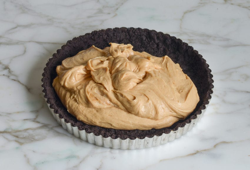 Tart pan with a chocolate crust and peanut butter filling.