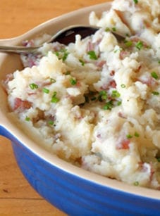 Spoon in a dish of parmesan smashed potatoes.