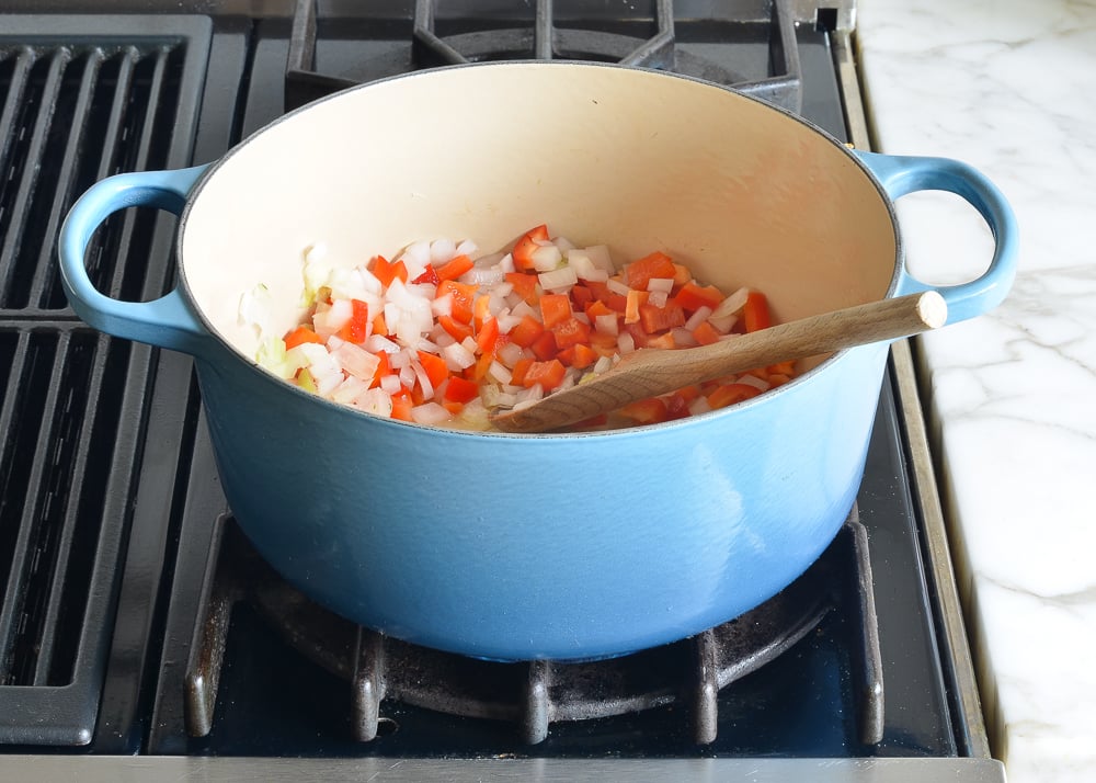 Onions and red peppers in a Dutch oven.