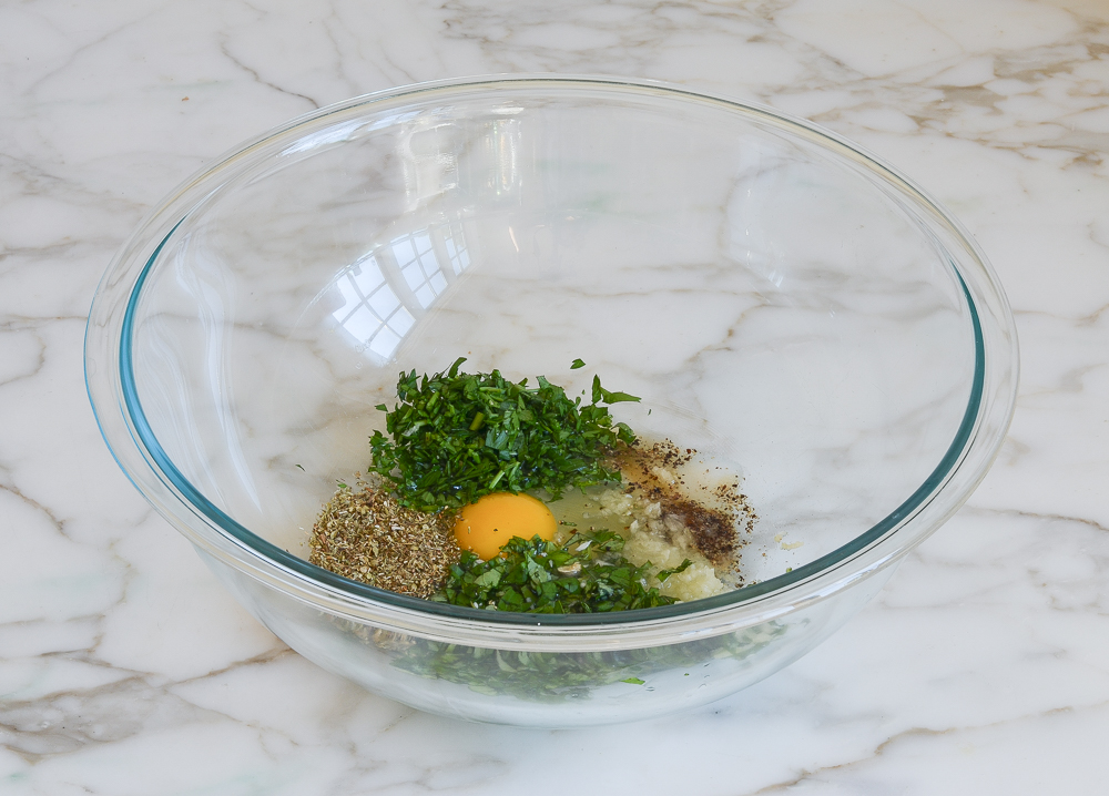 herbs, egg, water, and seasoning in mixing bowl