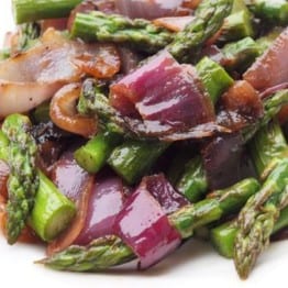 Plate of grilled asparagus and red onions with olive oil and balsamic vinegar.