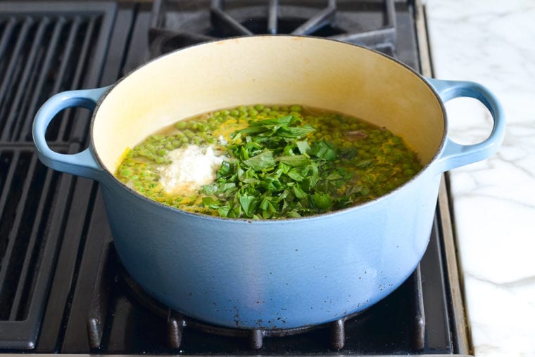 adding basil and cheese to pea soup
