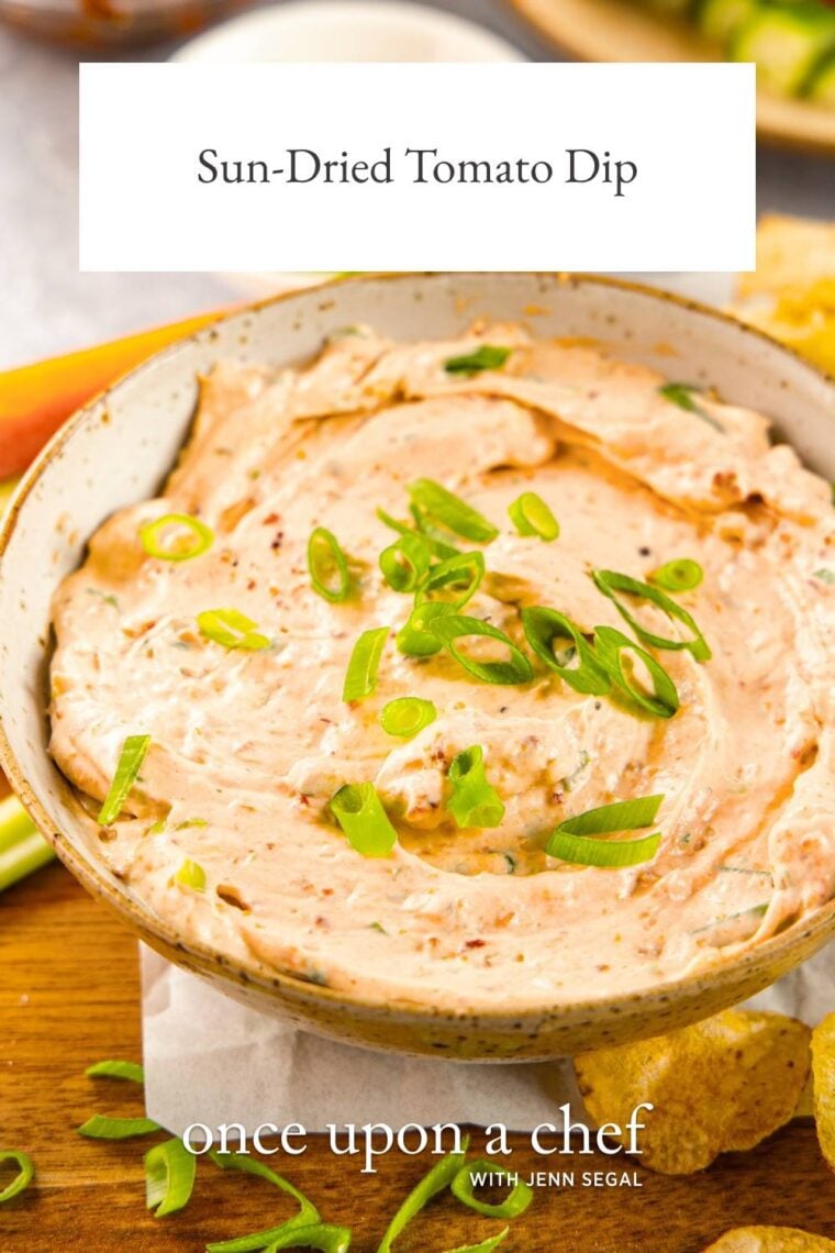 sun-dried tomato dip in ceramic bowl on wood cutting board