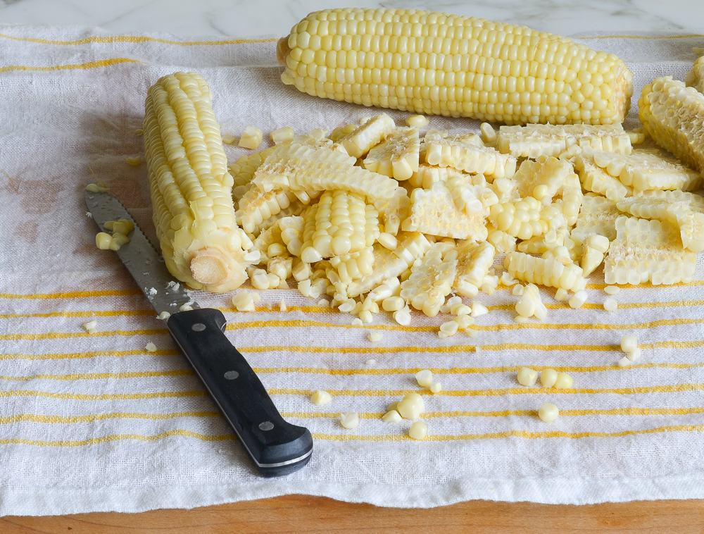 Corn cut from a cob next to a knife.