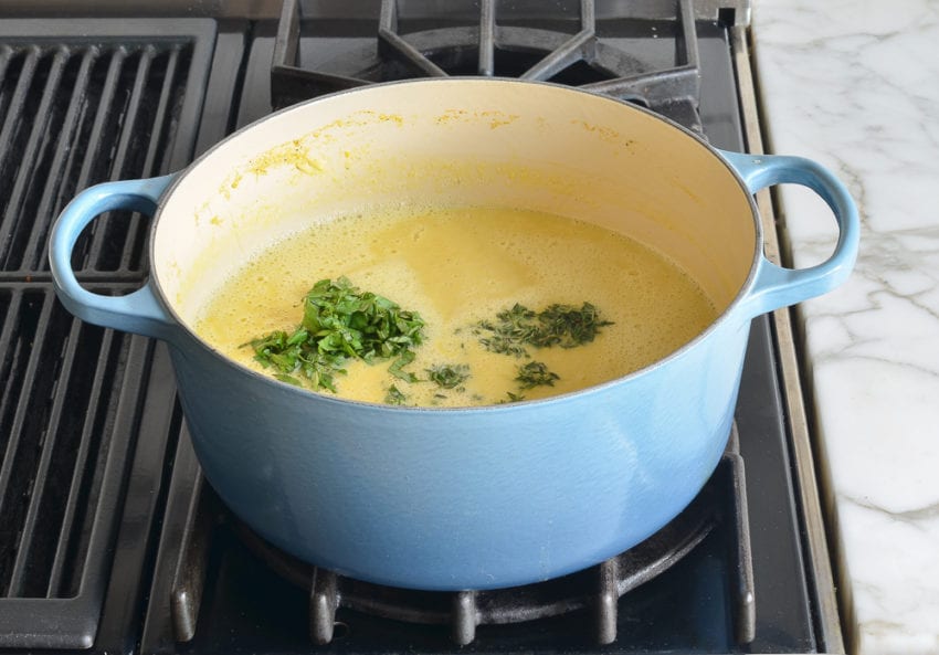 Fresh herbs in a Dutch oven of soup.