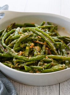 Dish of roasted green beans with garlic, lemon, pine nuts, and parmesan.