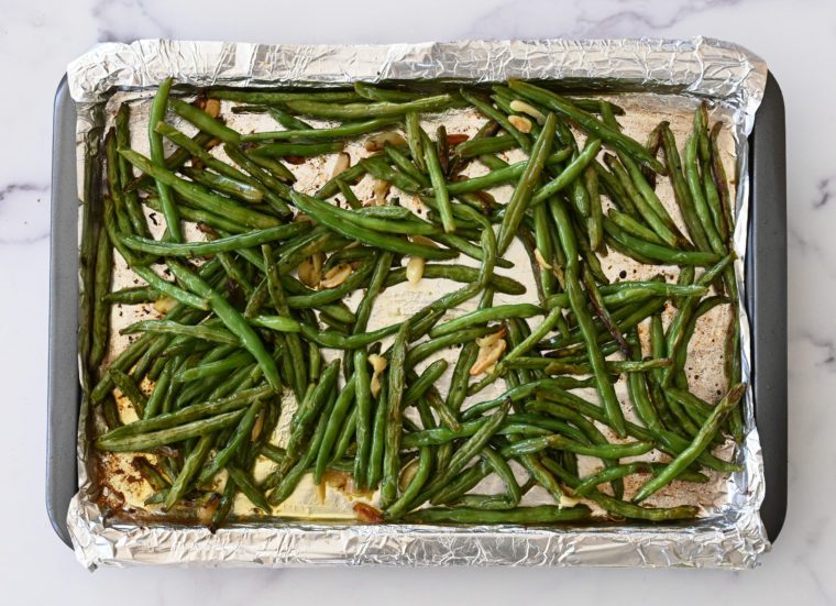 tossed roasted green beans on baking sheet