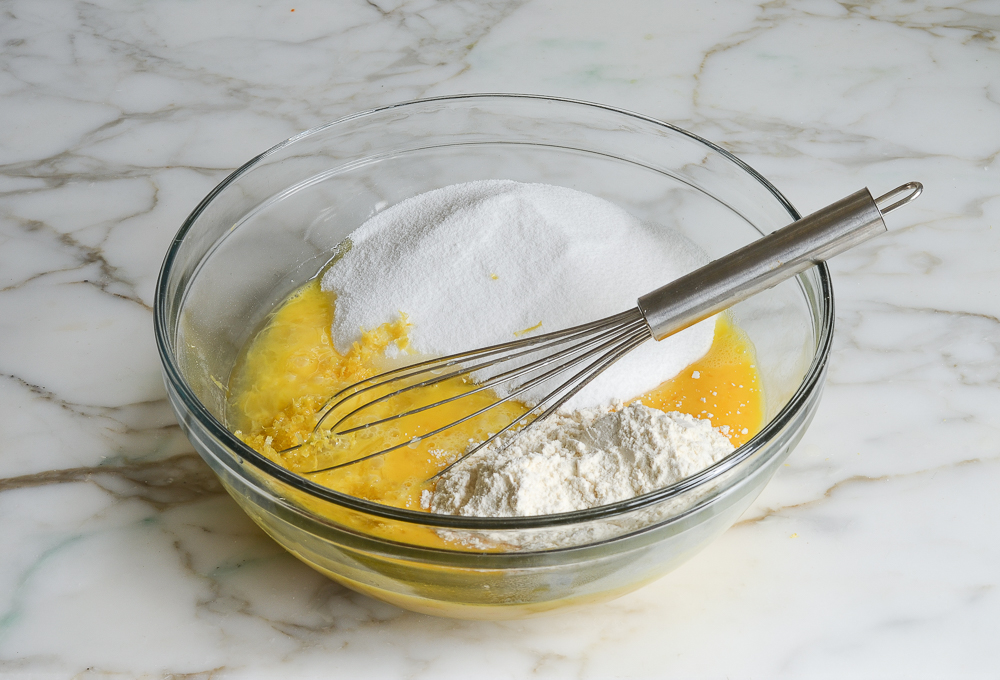 adding sugar, lemon, and flour to eggs for filling
