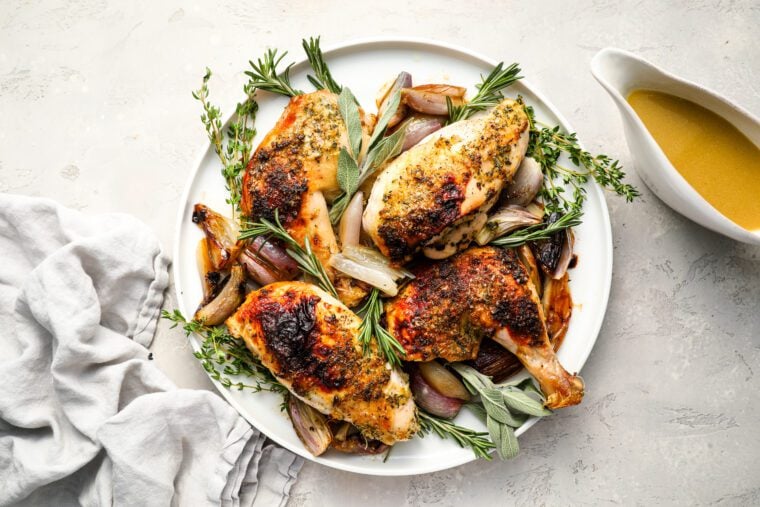 roast chicken on platter with sauce on side.