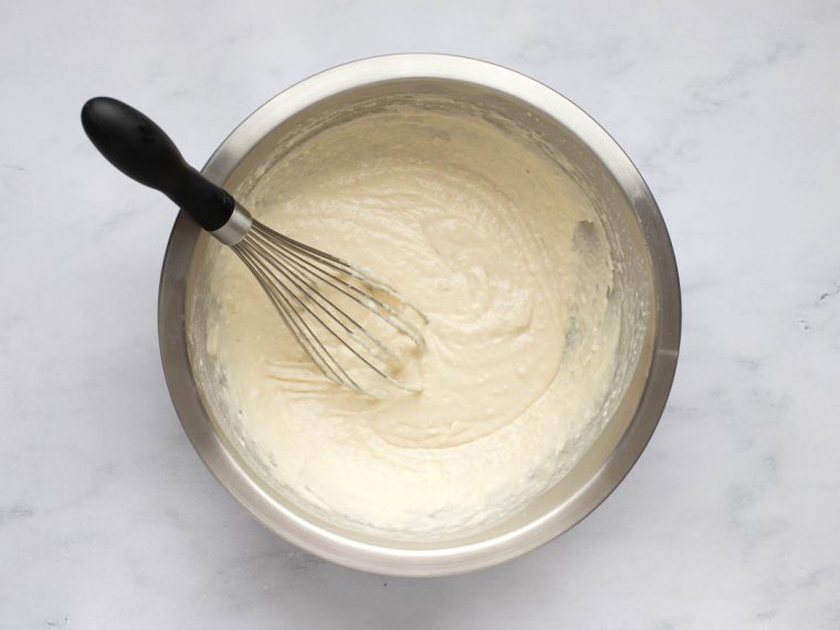 Yeasted waffle batter in a bowl with a whisk.