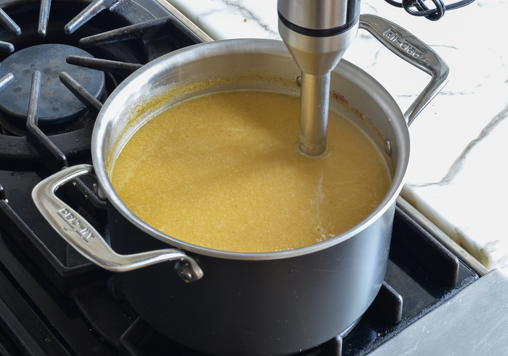 Immersion blender in a pot of smooth soup.