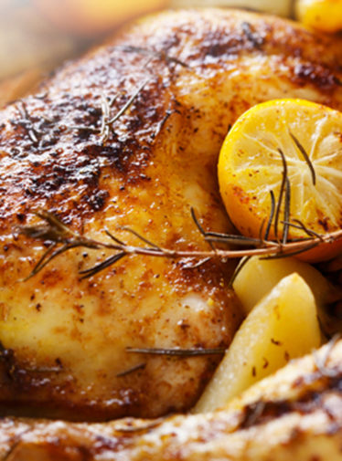 Roast chicken with herb butter and lemon slices.