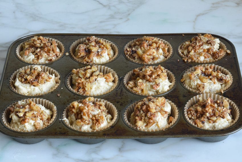 banana nut muffin batter in muffin cups with walnut topping