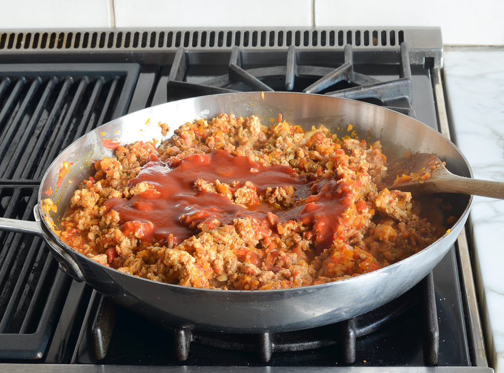 Tomato sauce in a skillet with ground chicken.