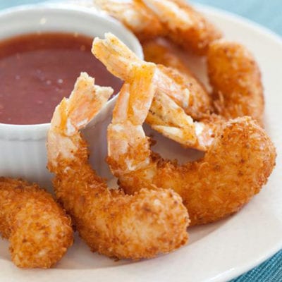 White plate of coconut shrimp with dip.