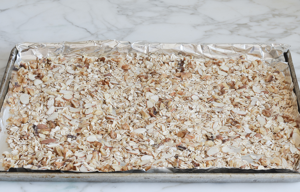 oats and nuts spread on baking sheet.