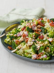 Spoon on a plate of broccoli salad with bacon, cheddar, and almonds.