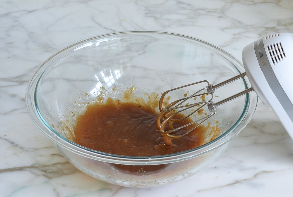 The butter and sugar mixed in a glass bowl with a mixer to the side.