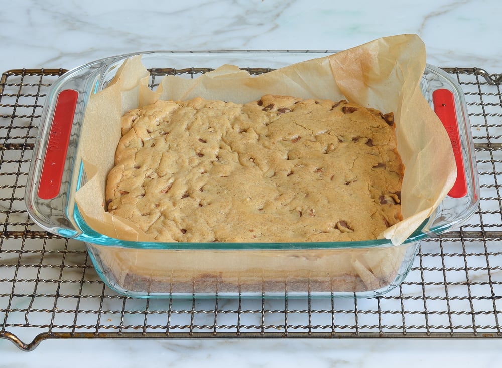 Lined baking dish of baked blondies.