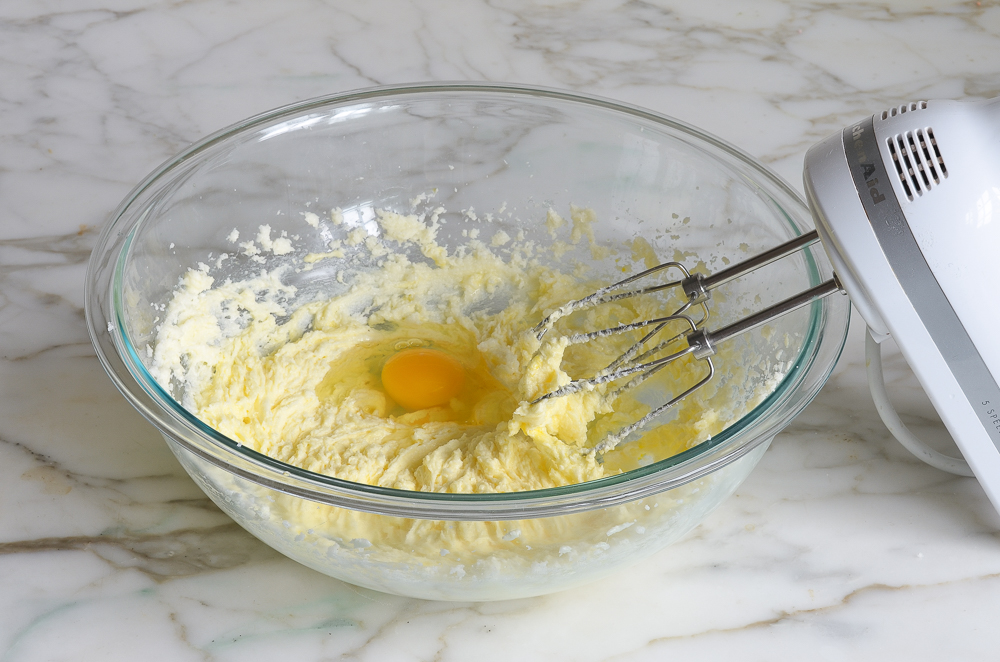 Egg in a bowl of creamed butter and sugar.