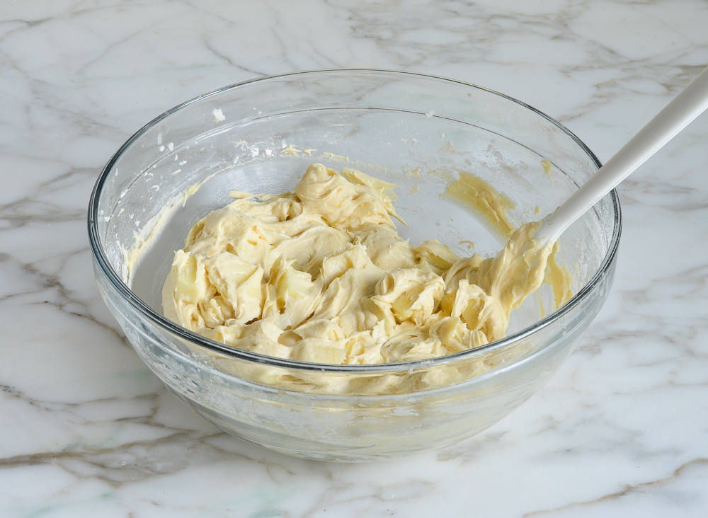 Apples and cake batter folded in a bowl.