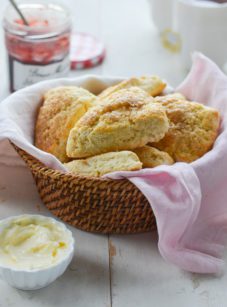 basket of scones with butter and jam.