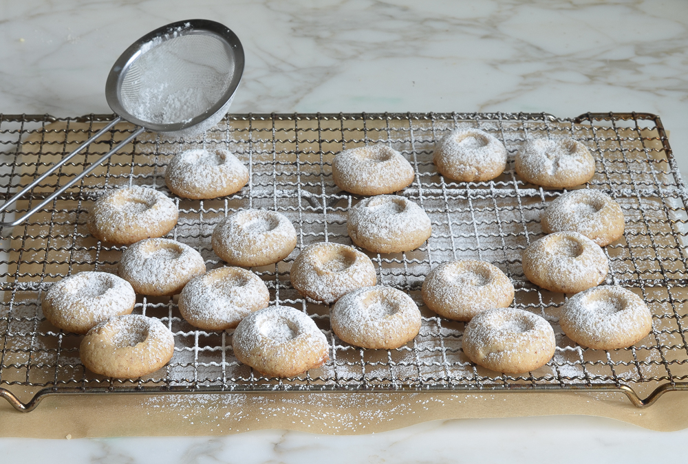 Sieve dusting powdered sugar on cookies.
