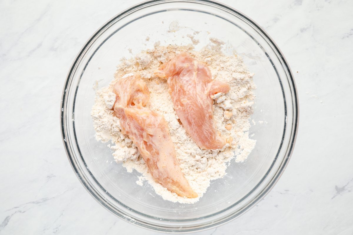 Breading chicken tenderloins for frying.