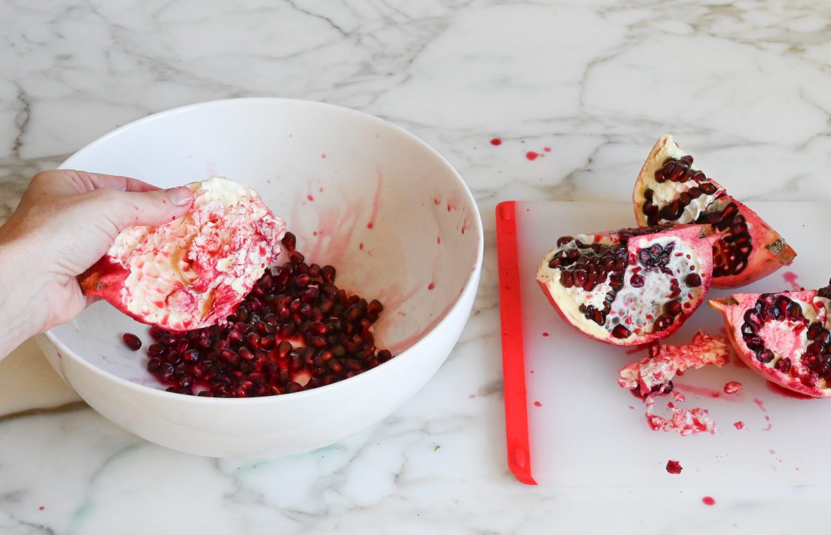 releasing the pomegranate arils into the bowl