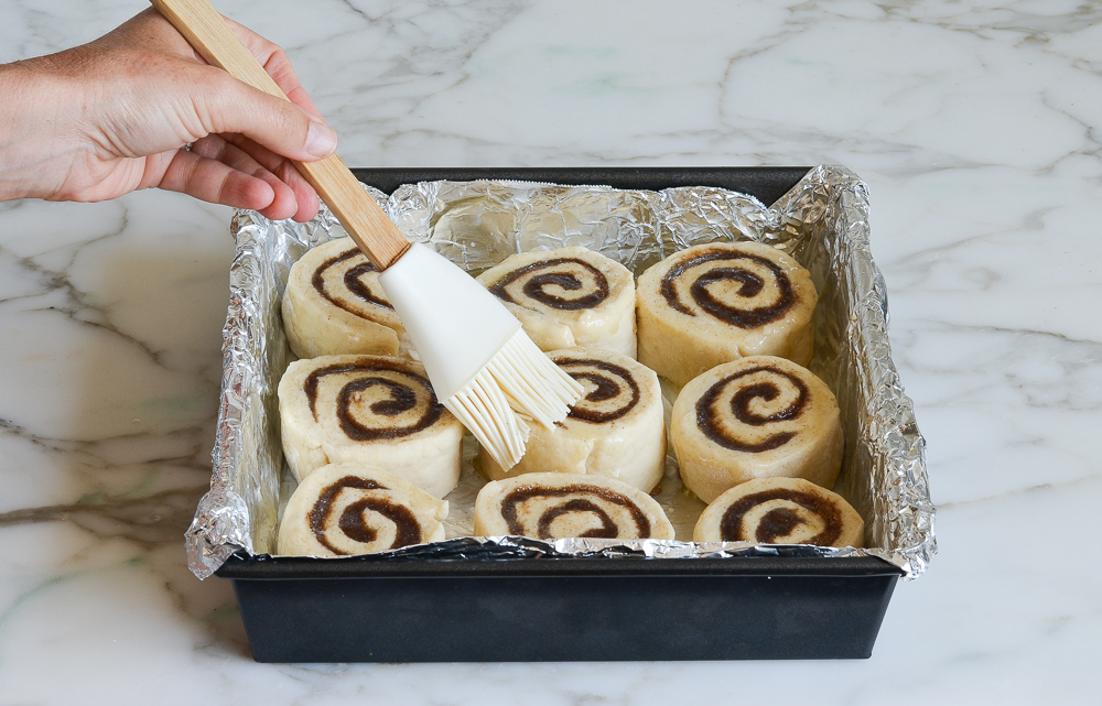 brushing cinnamon buns with butter