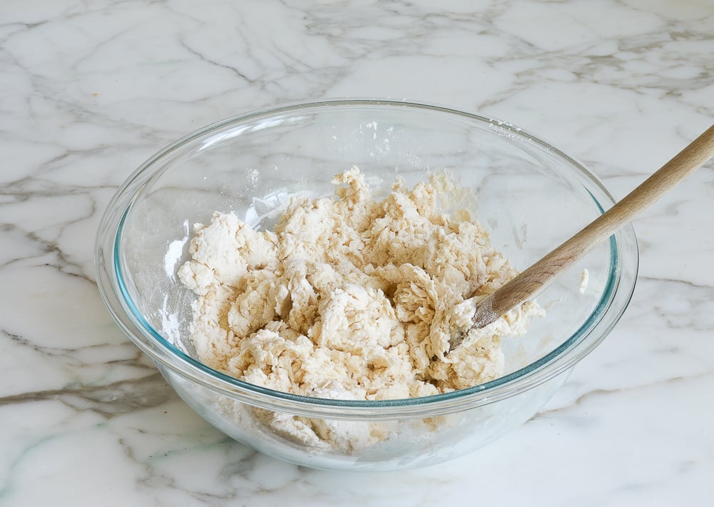 Shaggy dough in a bowl with a wooden spoon.