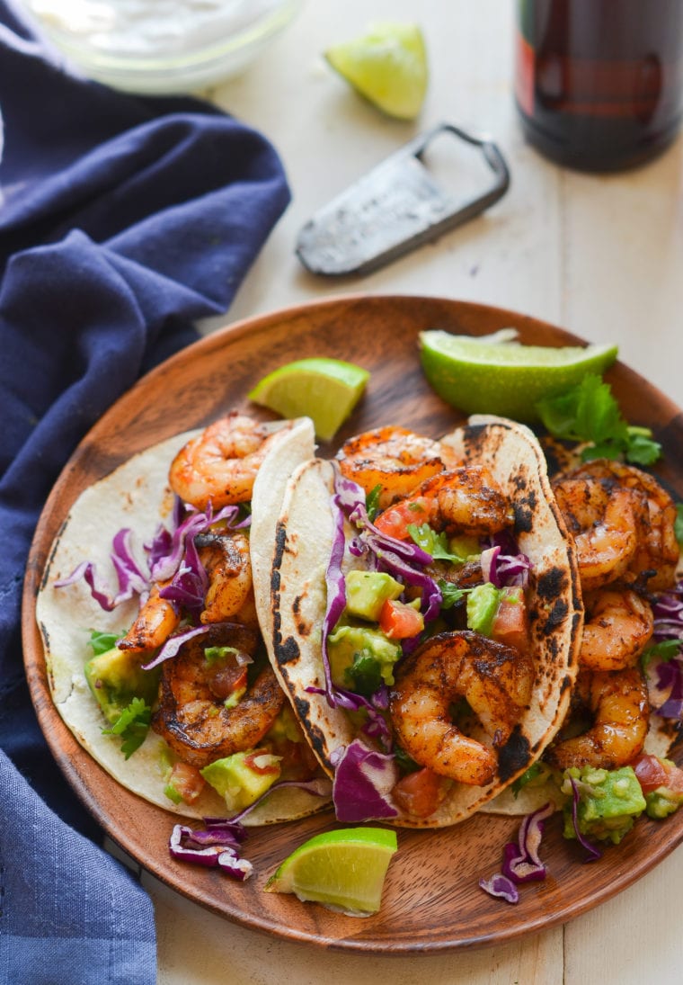 Grilled shrimp tacos on a wooden plate.