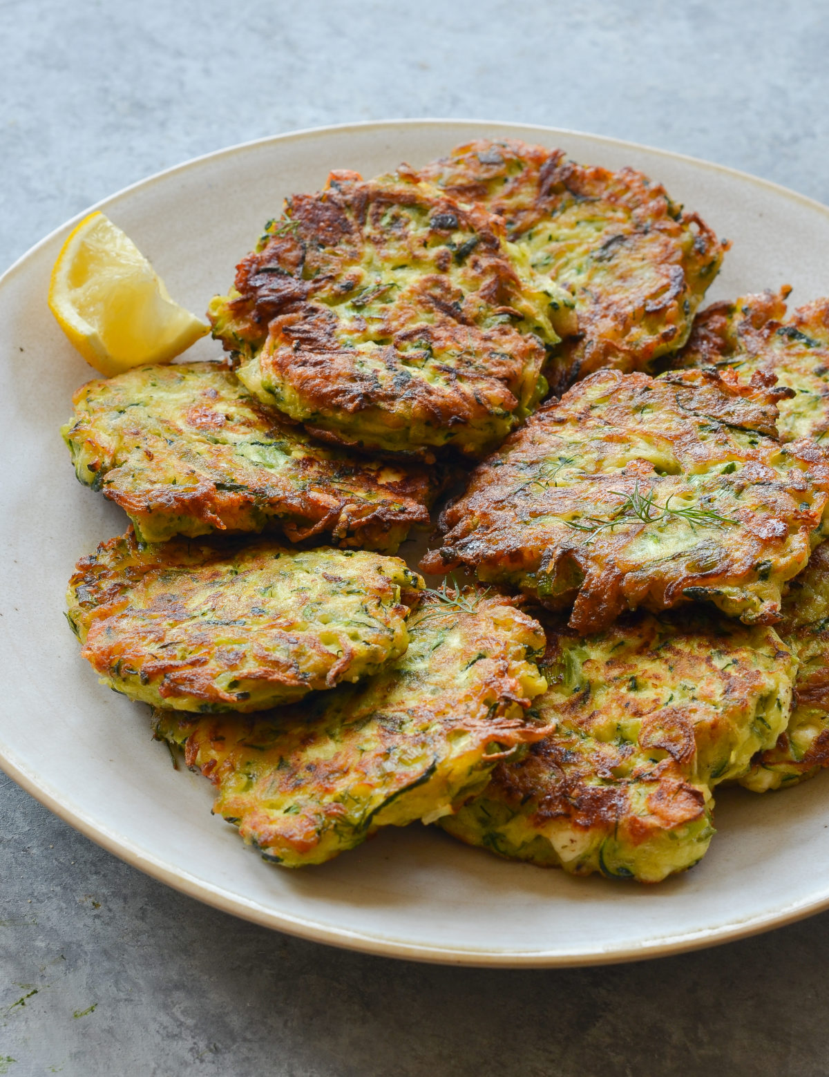 Plate of zucchini fritters with feta and dill.