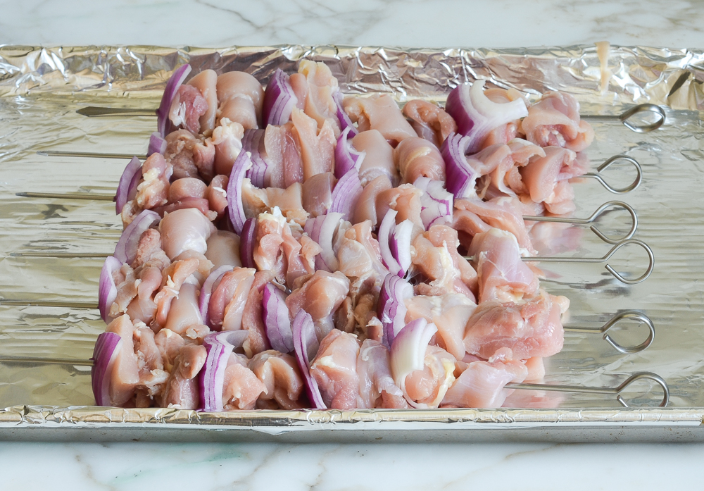 threading chicken and onions on skewers