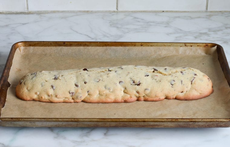 Log of chocolate chip Mandel bread on a lined baking sheet.