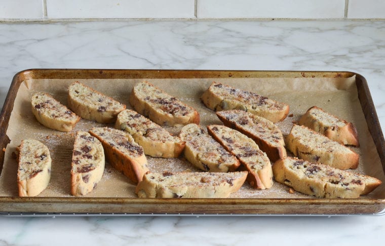 Slices of chocolate chip Mandel bread on a lined baking sheet.