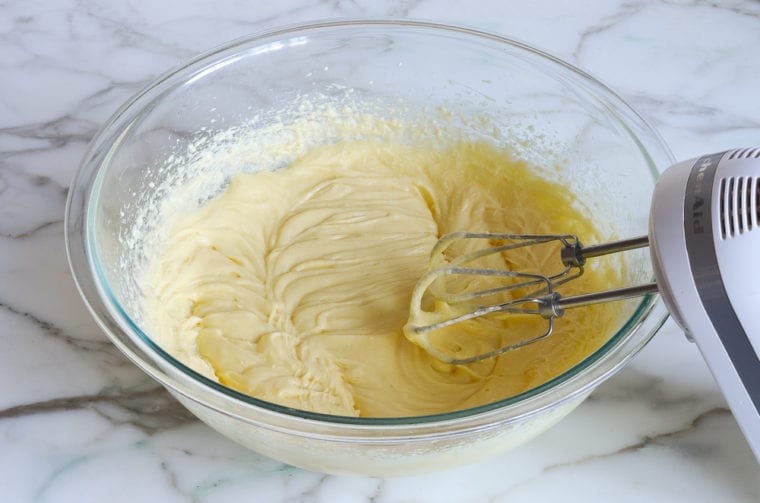 Electric mixer in a bowl with a butter and egg mixture.