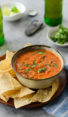Bowl of roasted tomato salsa on a plate with chips.