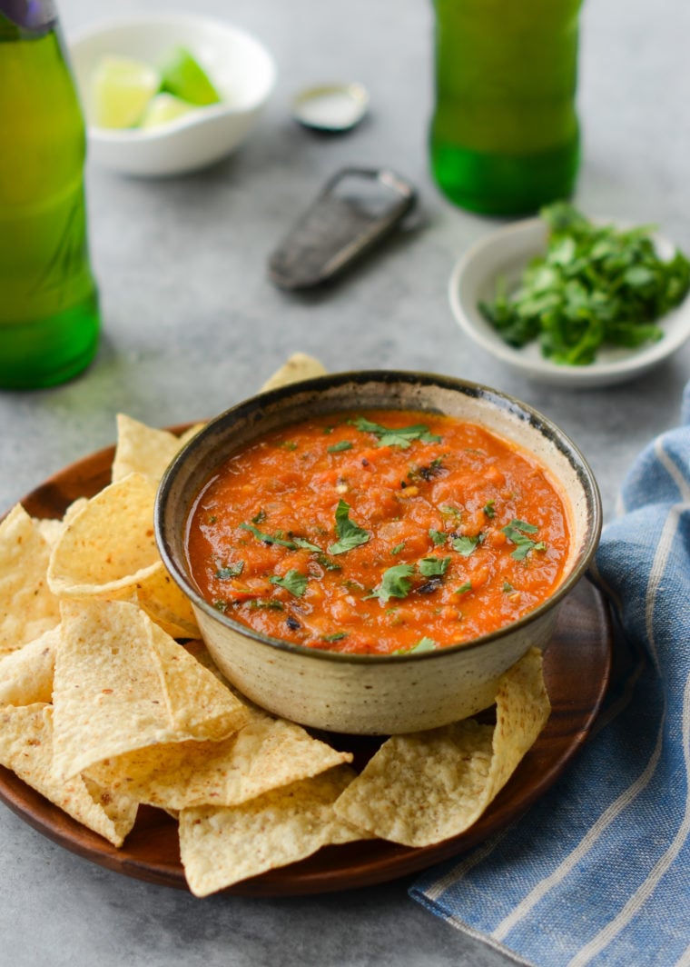 Bowl of salsa on a plate with chips.