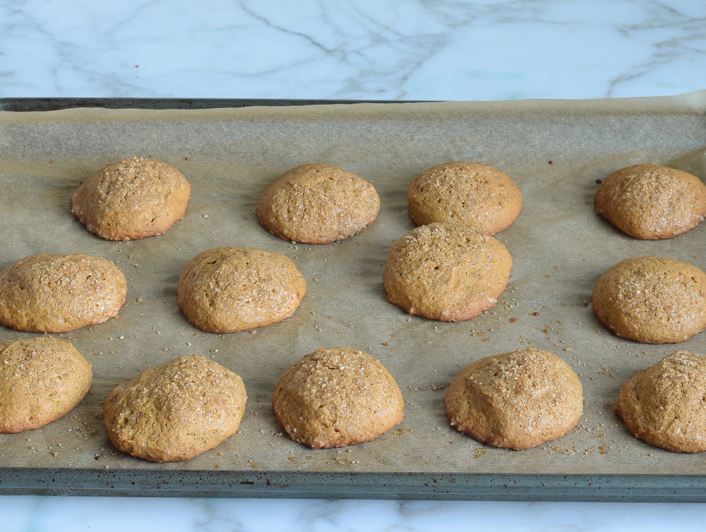 Pumpkin cookies on a lined baking sheet.