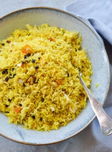 Fork on a plate with basmati rice pilaf with dried fruit and almonds.