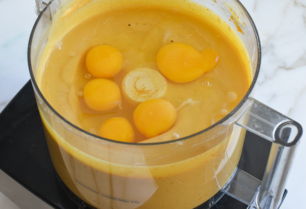 Eggs on a light orange mixture in a food processor.