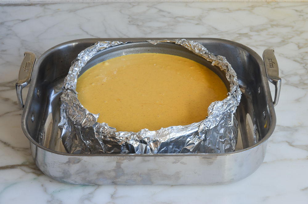 Light pumpkin mixture in a foil-wrapped pan set in a roasting pan.