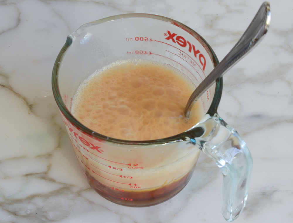 Spoon in a measuring cup with heavy cream.